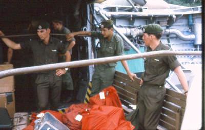 Flintoff,  ??  ,  Schwass - red bags are mail, the troops are standing on a truck deck backed up to the front of the aircraft, the aircraft doors are extended behind the soldiers    [Young]